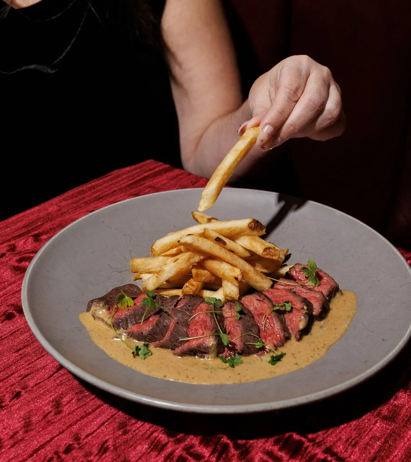 Steak frites plated with herbs and sauce at Wright & Company